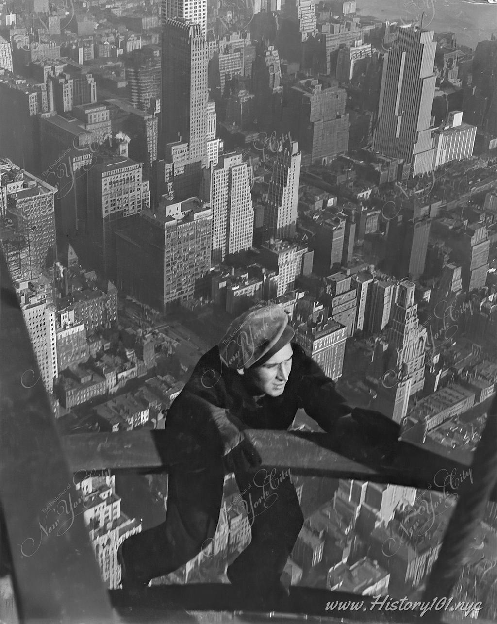 A work clings to the steel framing of the future Empire State Building with a bird's eye view of Midtown Manhattan, many stories below him.